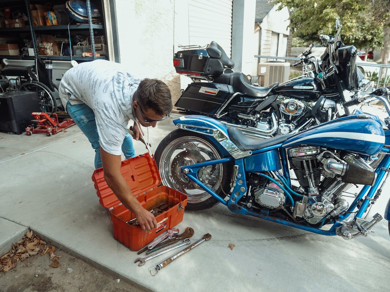 Home Man working on motorcycle repair with tools in a garage setting.